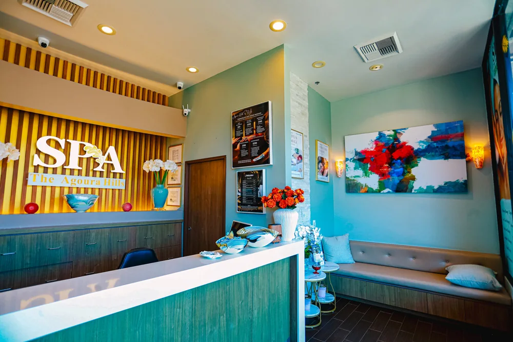 Teal reception lobby with a gold SPA — The Agoura Hills sign and white orchids