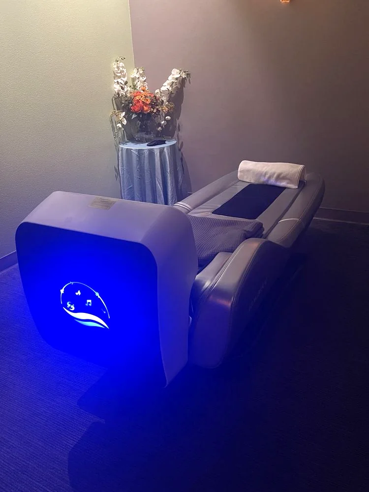 iRelaxbot robotic massage bed with a glowing blue control panel under purple ambient light